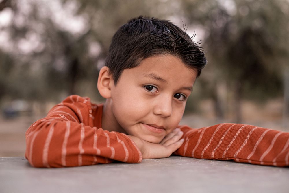 Close-up portrait series of a child in an orange striped shirt against a neutral background.