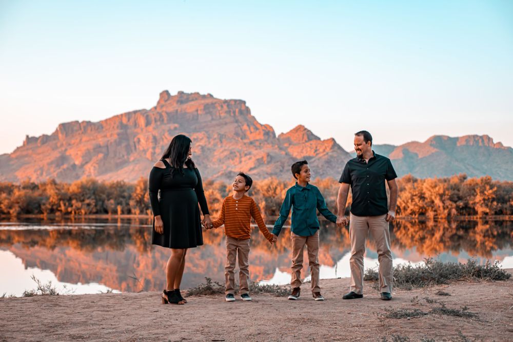 Silhouettes of a family walking together against a desert mountain landscape at sunset.
