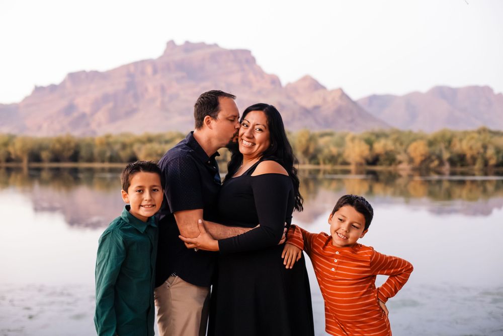Family enjoying playful moments together during outdoor photoshoot by mountain lake.