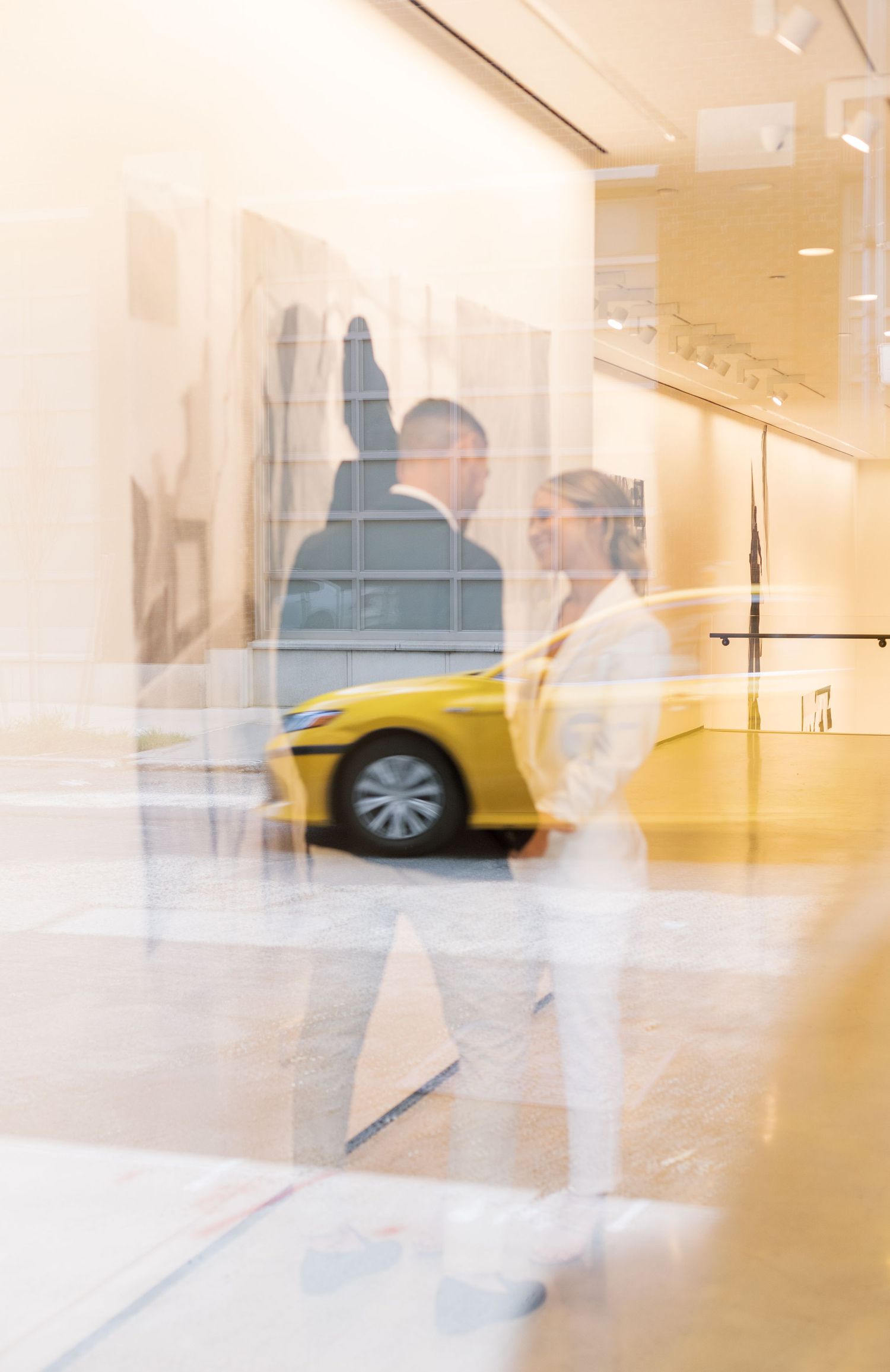 Blurred artistic reflection through glass with yellow taxi visible in the background.