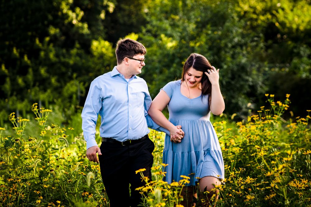 A couple shares a playful moment among blooming yellow wildflowers in a summer garden.