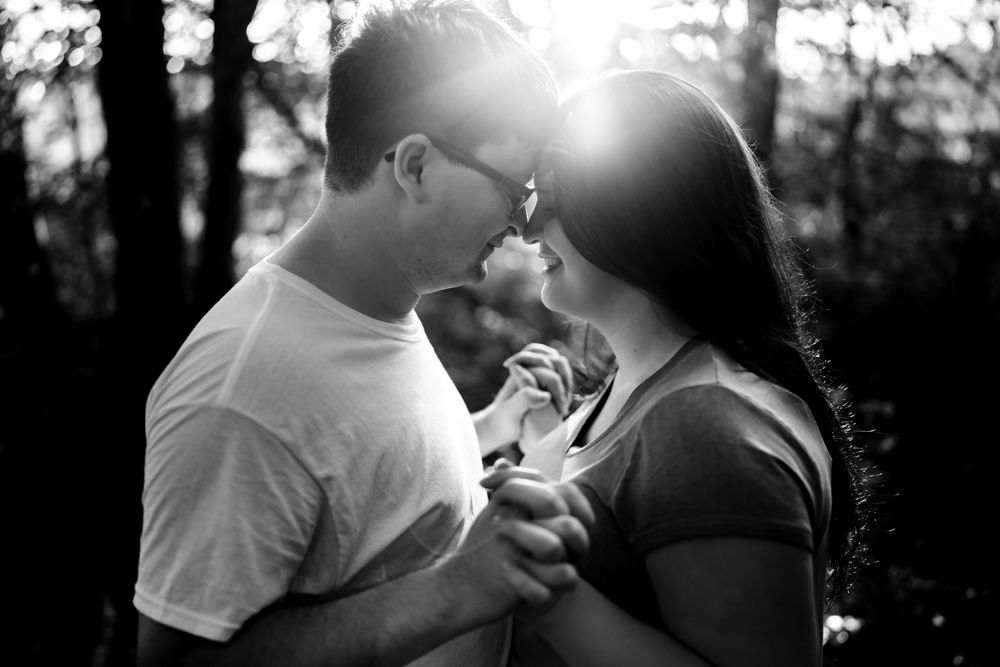 A backlit black and white portrait captures an intimate moment between a couple.
