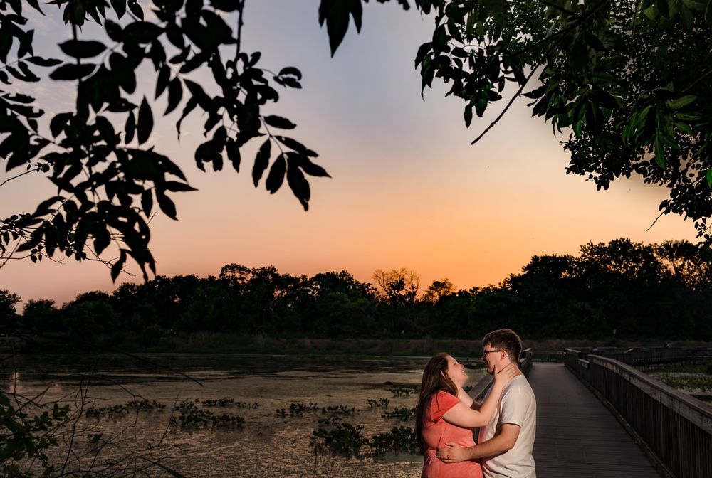 Romantic sunset silhouette of couple embracing in a park with tree branches framing the scene.