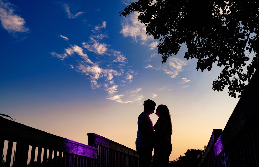 Silhouettes of trees and buildings against a vibrant blue sky with scattered clouds at dusk.