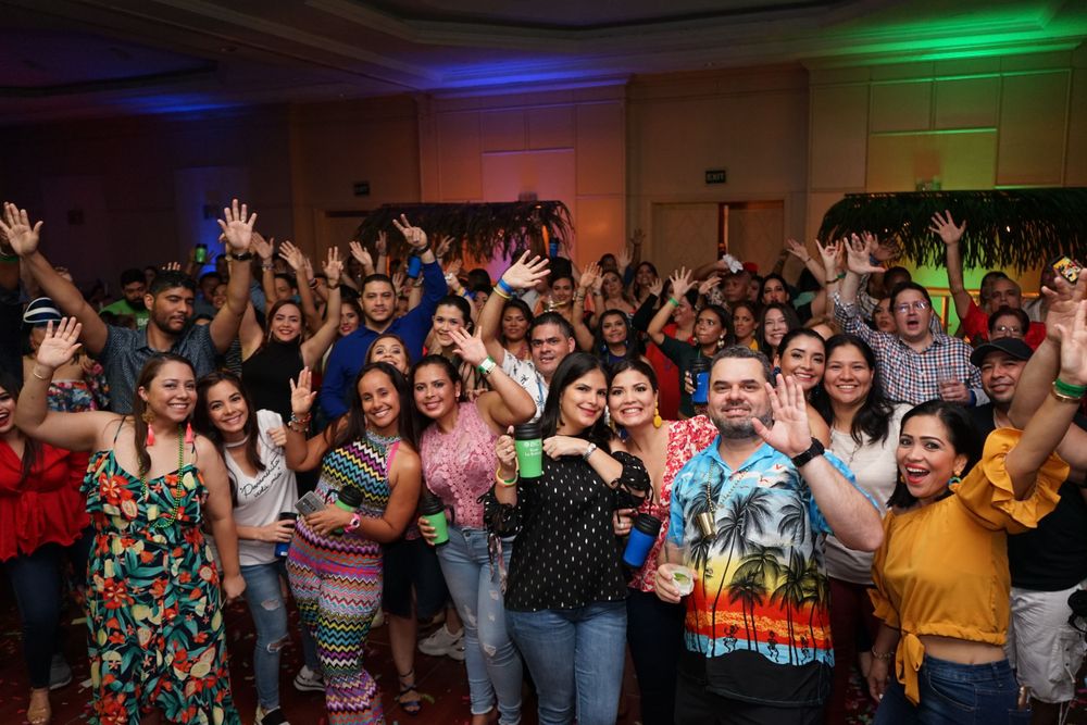 Enthusiastic crowd with raised arms enjoying a lively indoor concert performance.