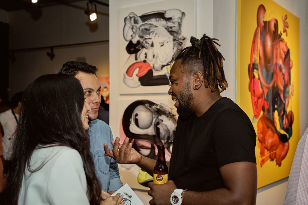 Small group of people having an animated conversation at an art gallery exhibition.