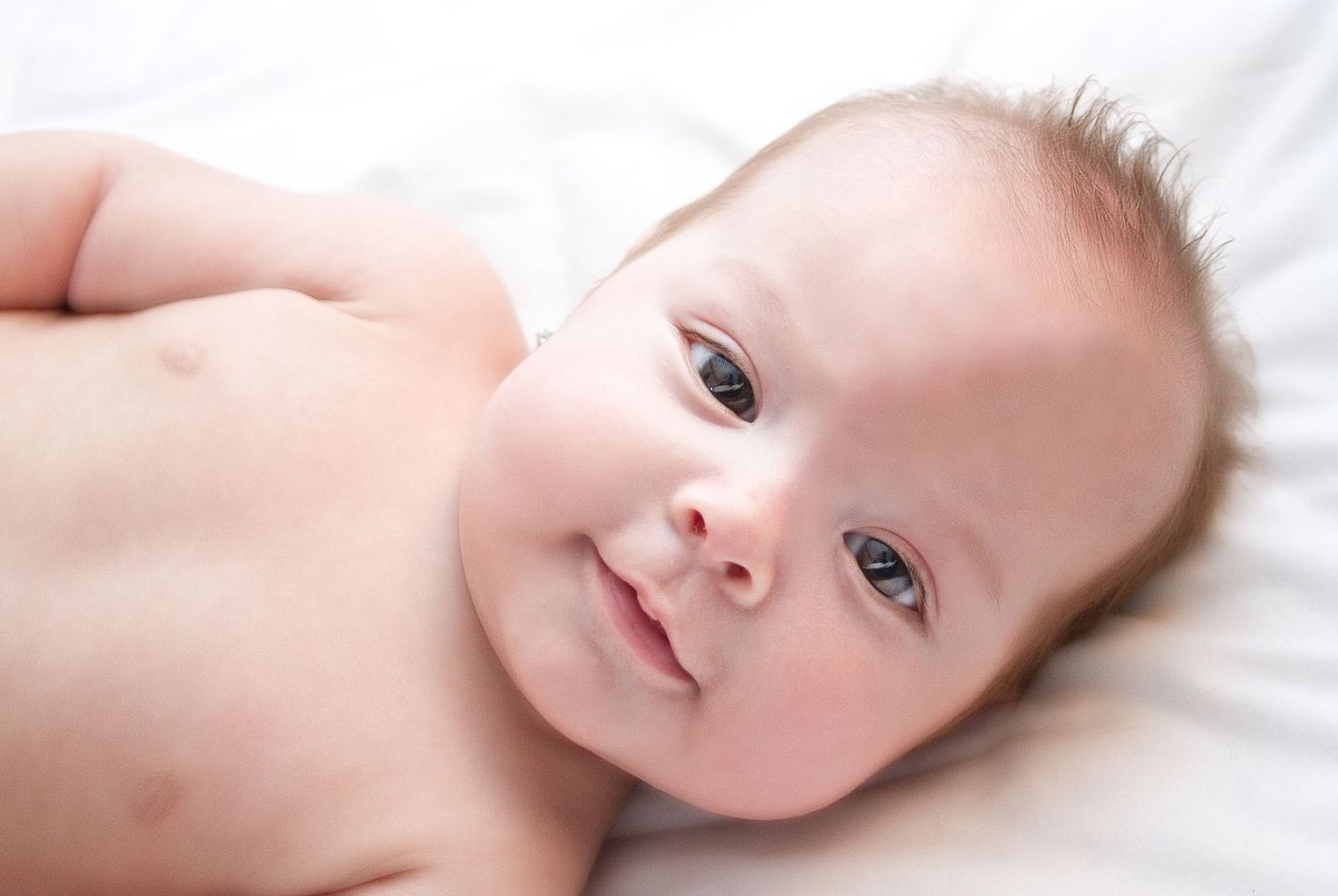 Gentle portrait series of baby with bright eyes against white background.