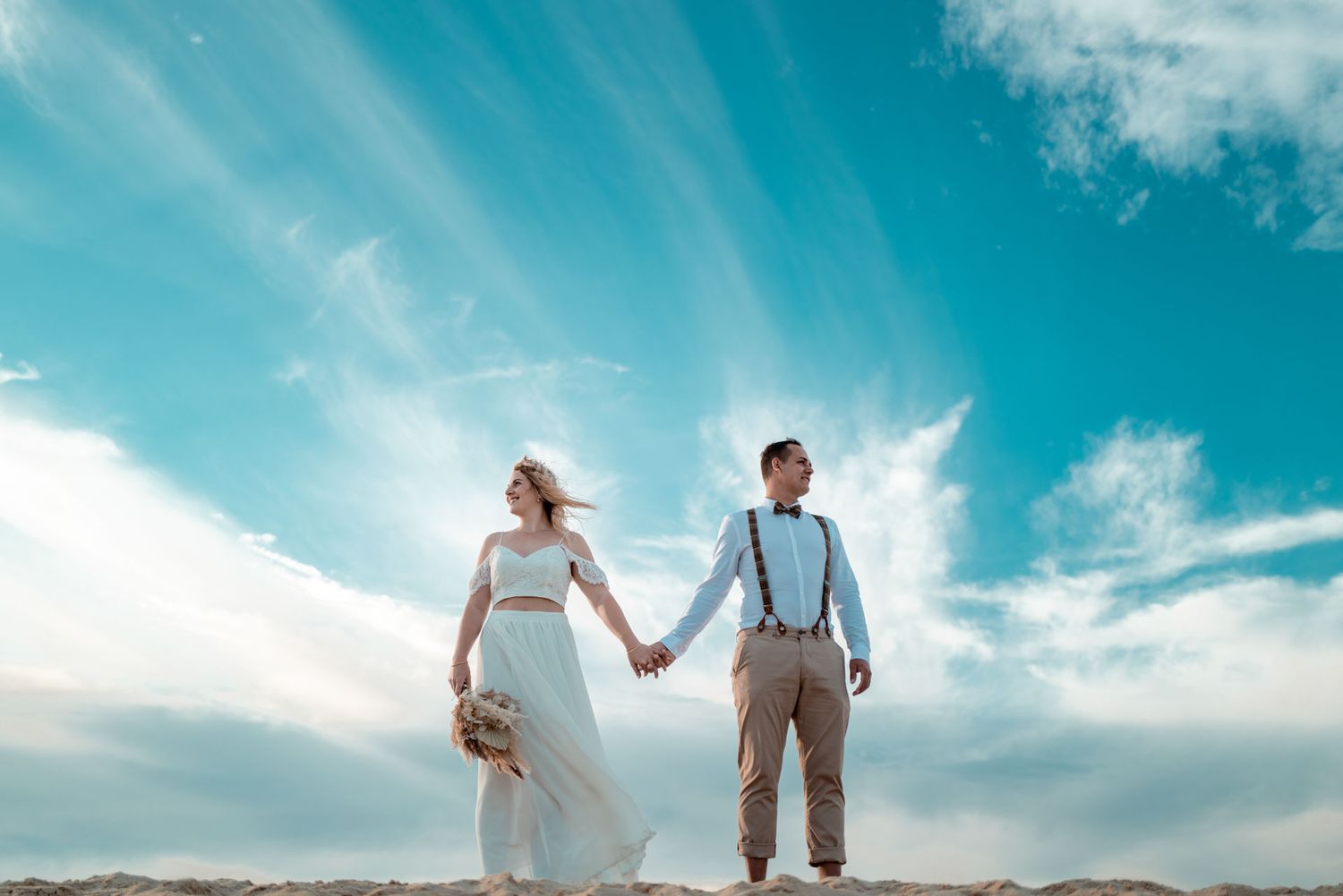 Brautpaar hält Händchen am windigen Strand bei einem herbstlichen Elopement fotografiert von Fabio Marras