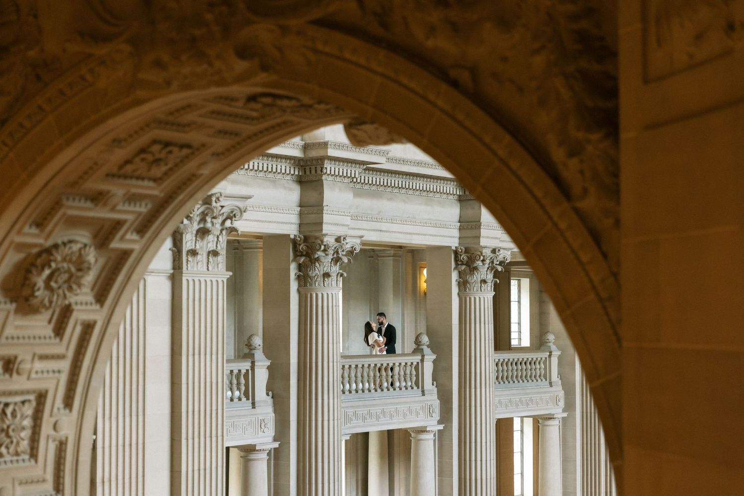 Architectural details of ornate classical columns and balconies viewed through a grand archway.