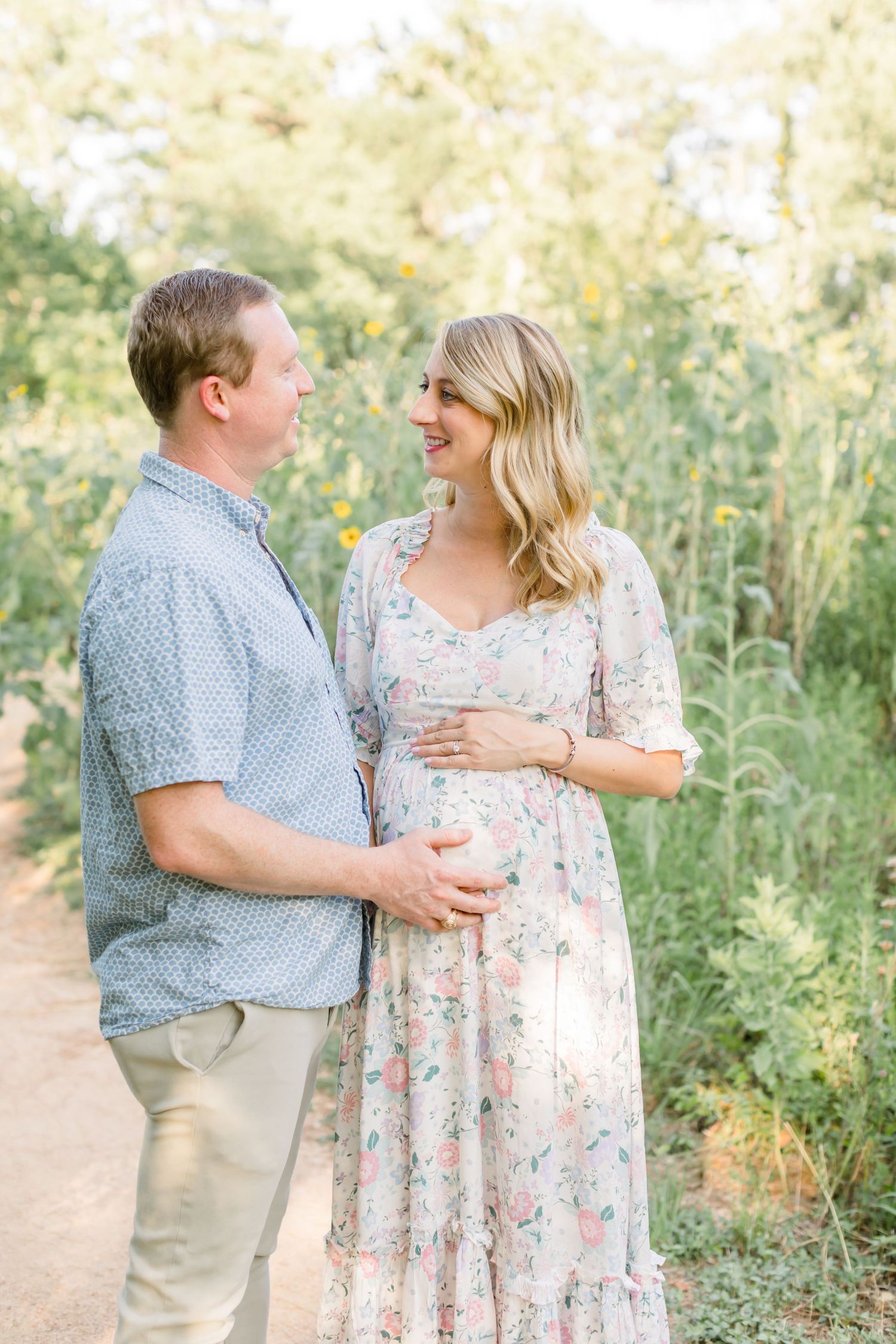 A couple shares an intimate moment on a nature trail while expecting their first child.