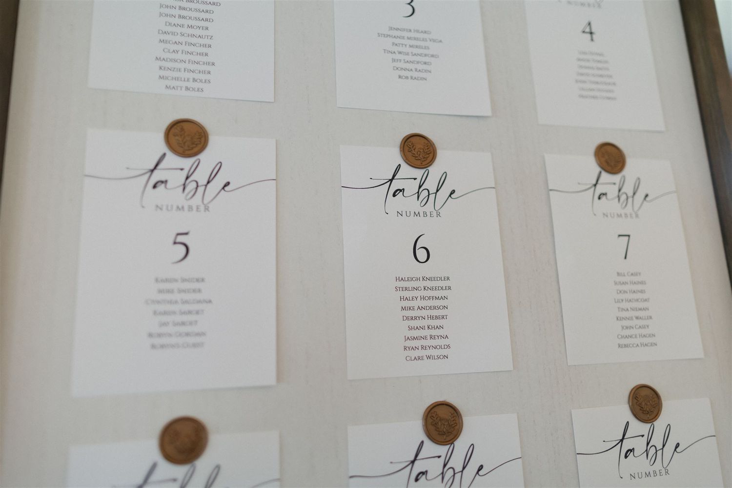 Elegant seating chart with wax seals and calligraphy displayed on white cards.