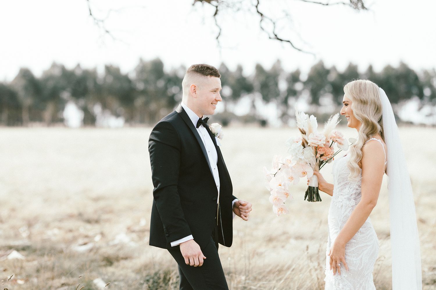 Elegant wedding portrait showing interaction between a couple against a natural outdoor landscape.
