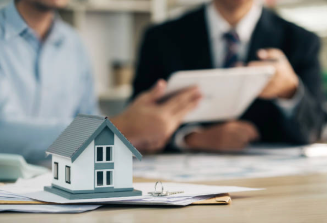 Small model house sits on paperwork during a real estate transaction.
