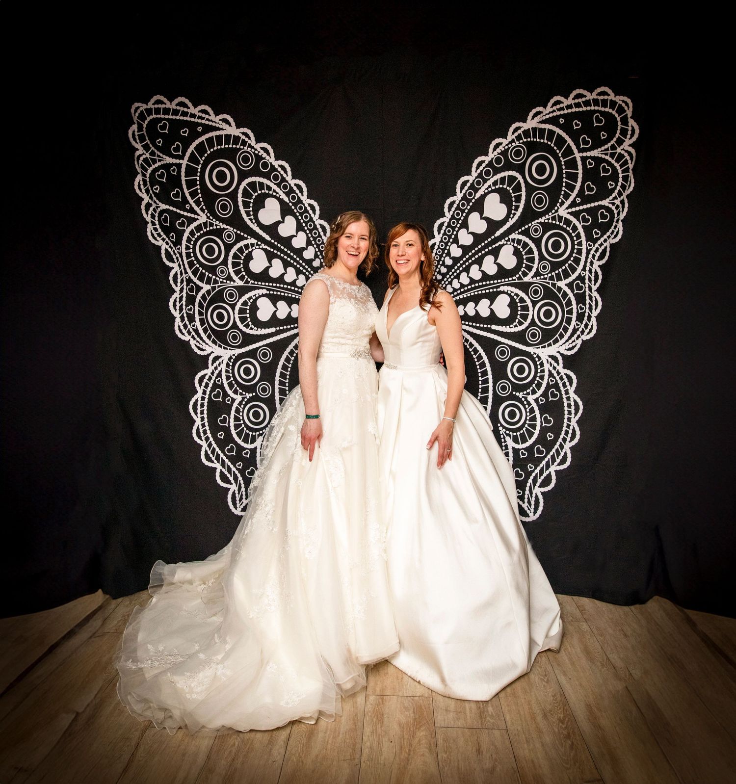 Creative wedding portrait with lace wing backdrop against black background.