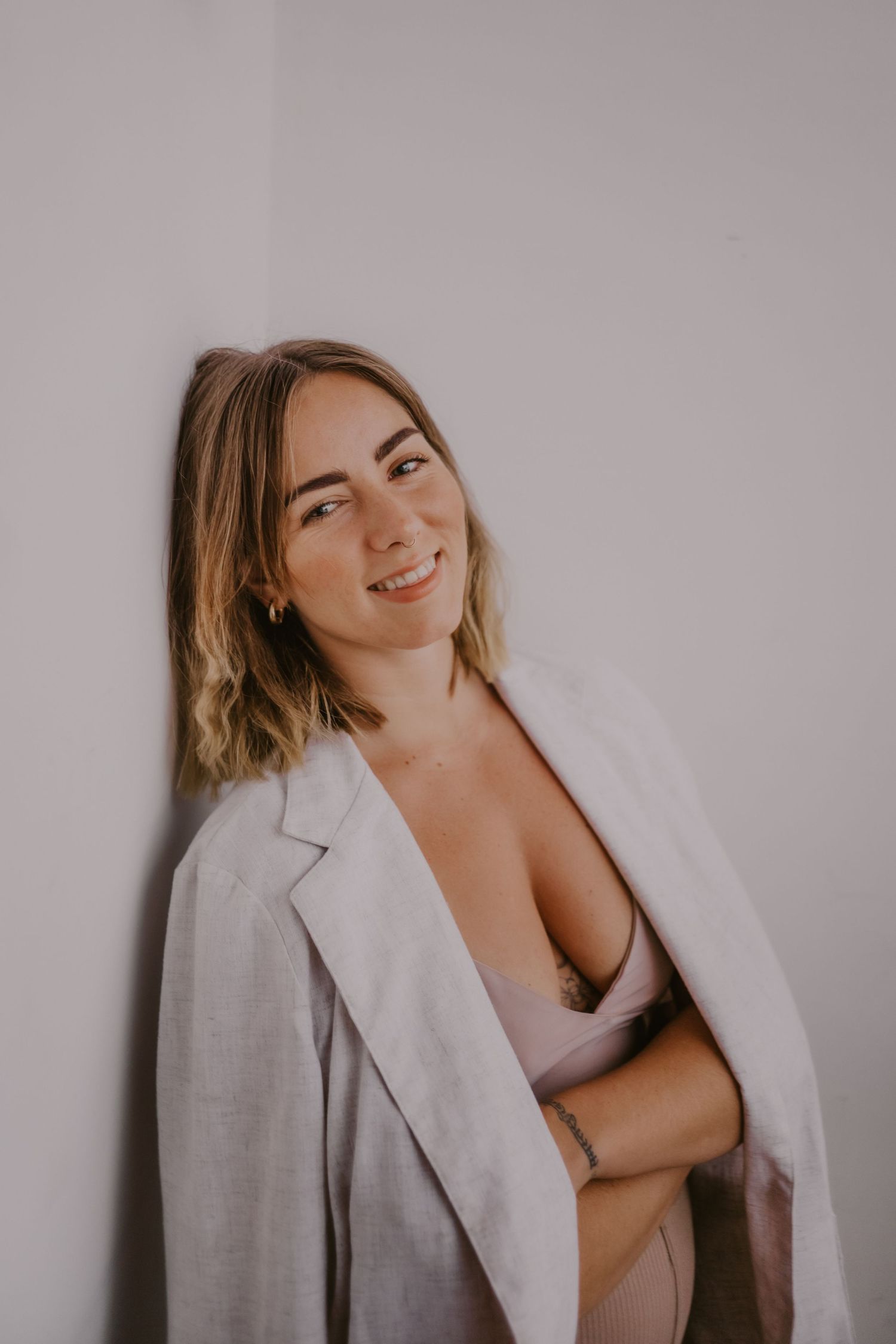 Artistic portrait of someone in white blazer against neutral wall.