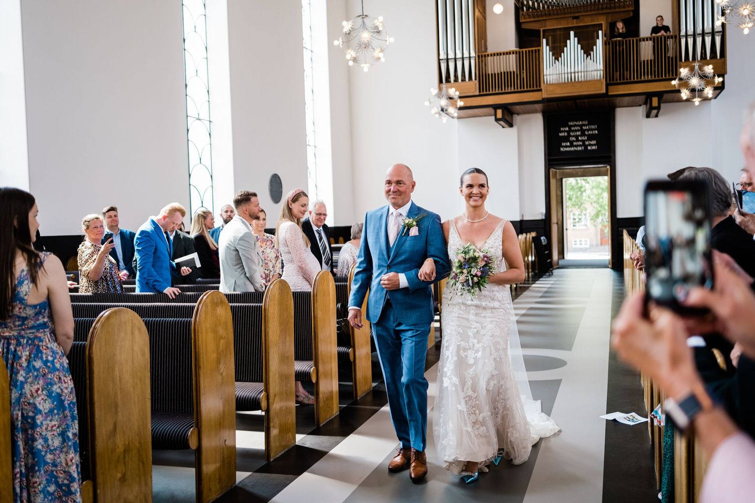 Wedding celebration in church with pipe organ and white decor.