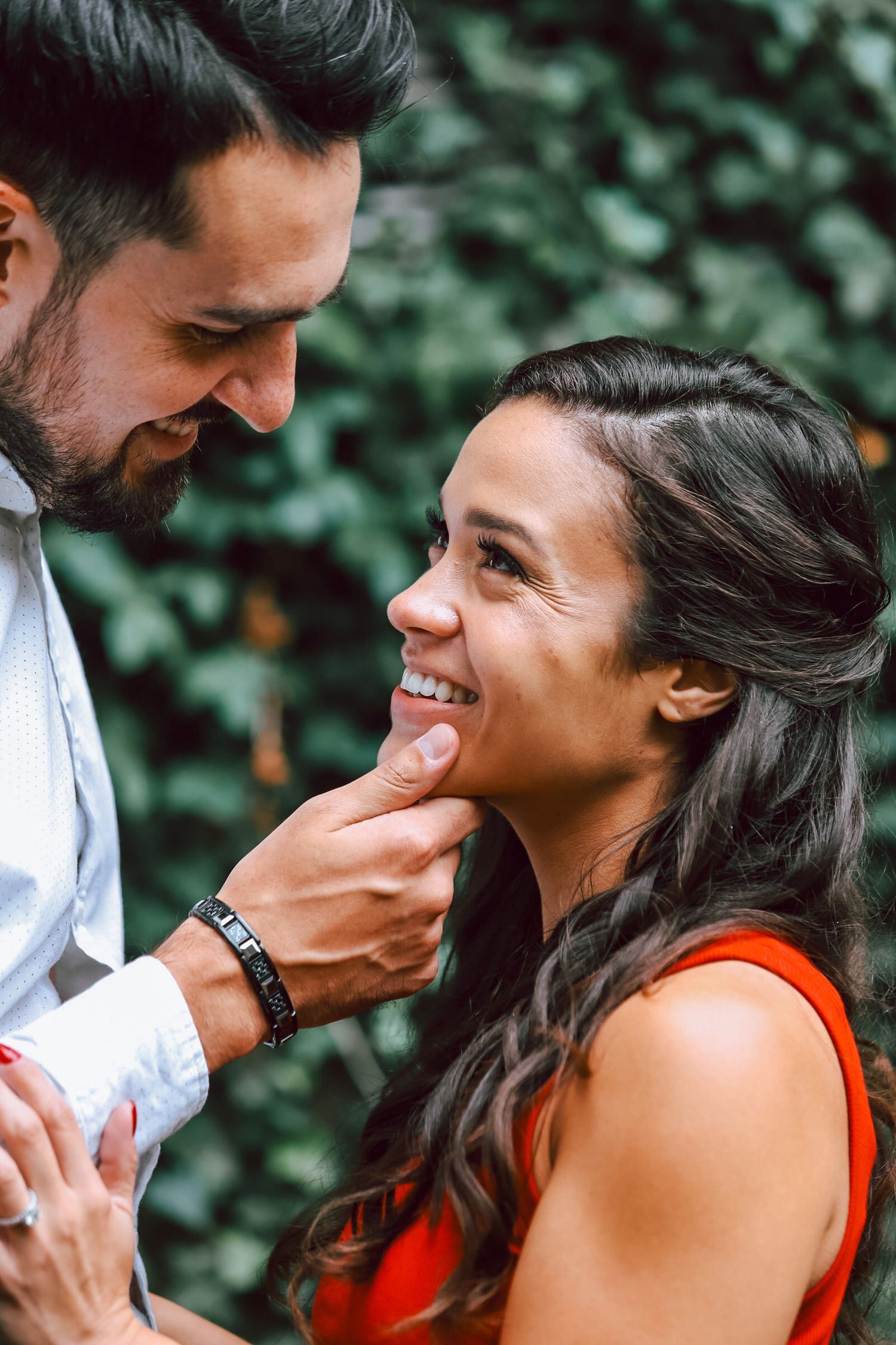 Candid outdoor couple photos showing genuine laughter and affection among greenery.