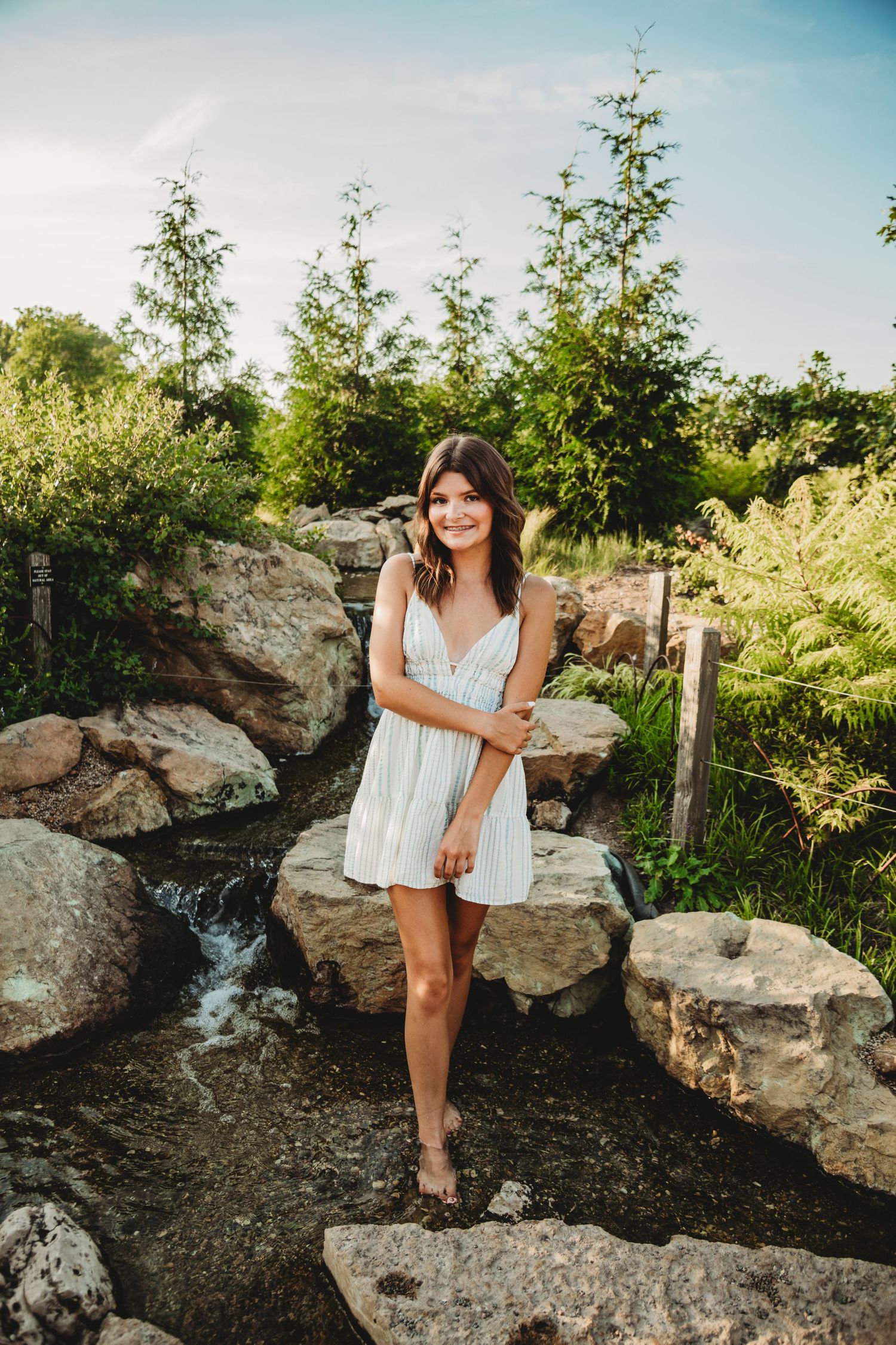 Summer portraits by rocky waterfall feature white flowing dress.