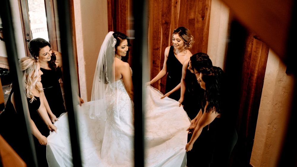 Behind-the-scenes moment of wedding preparation as attendants help with the dress.