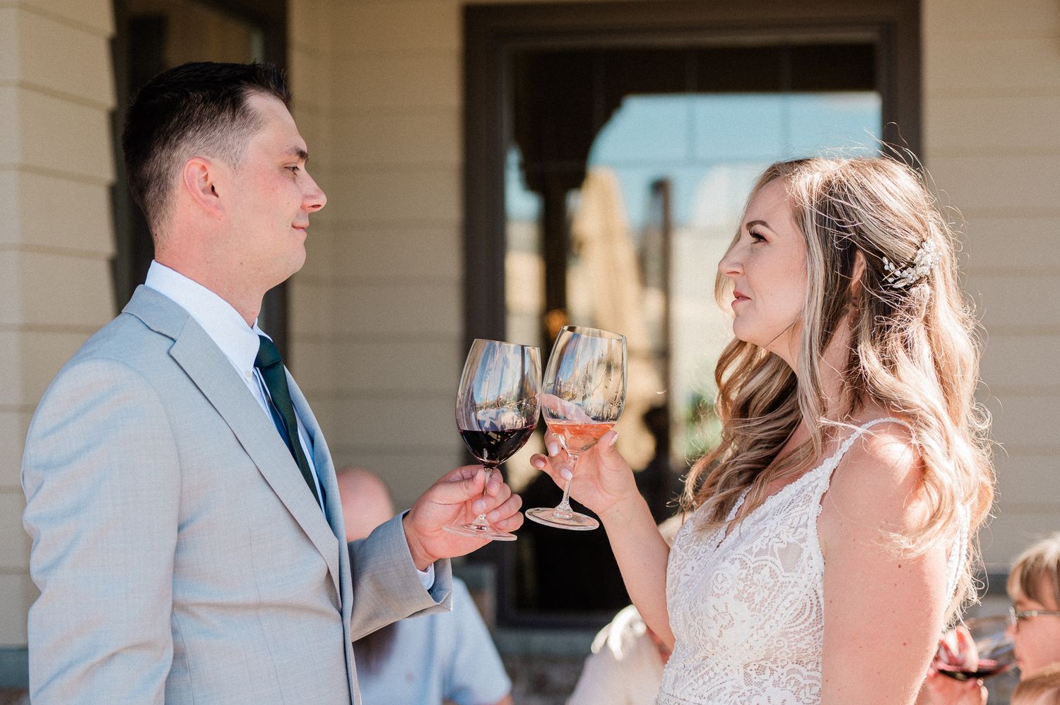 bride and groom staring at each other while wine tasting at winery.