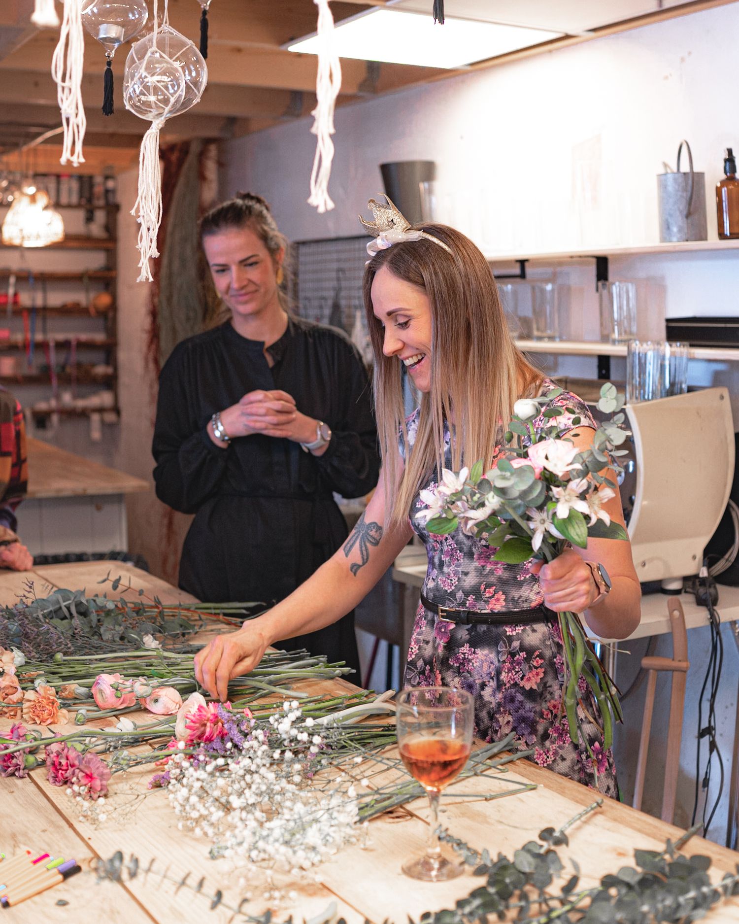 A floral arranging class in progress with wine and fresh flowers on a wooden workbench.