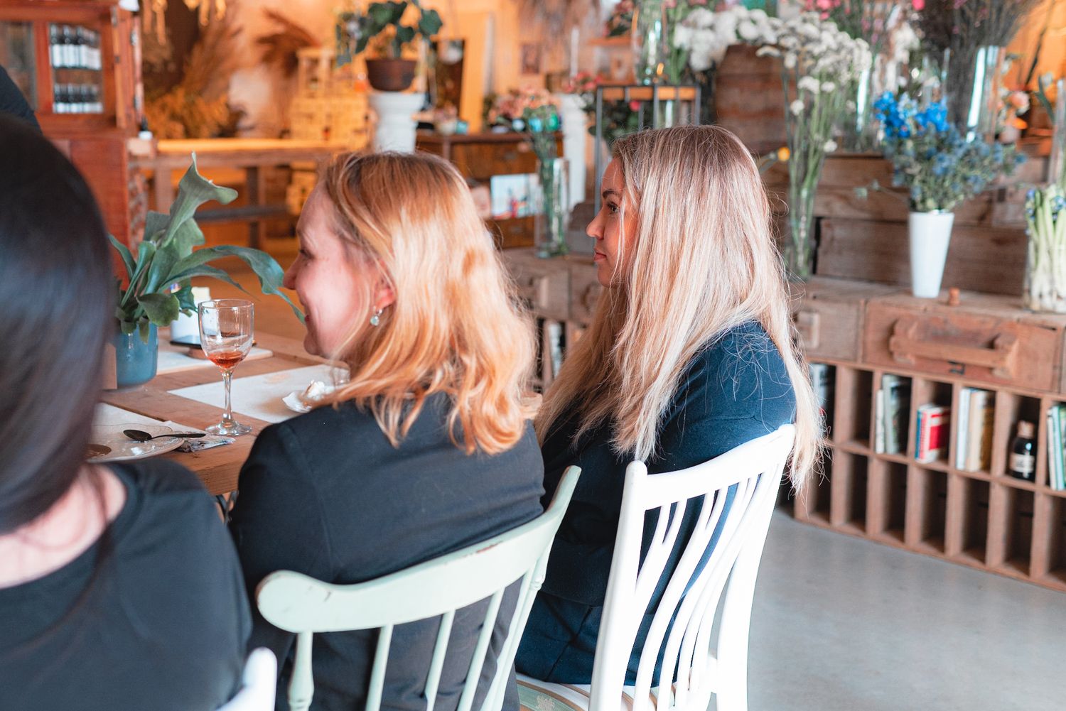 Group dining in a rustic restaurant interior with wooden furniture and plants.