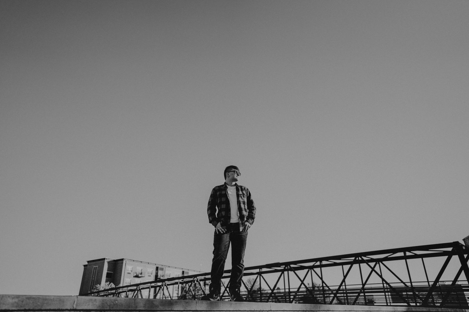 Silhouette of person standing on metal structure against grey sky.