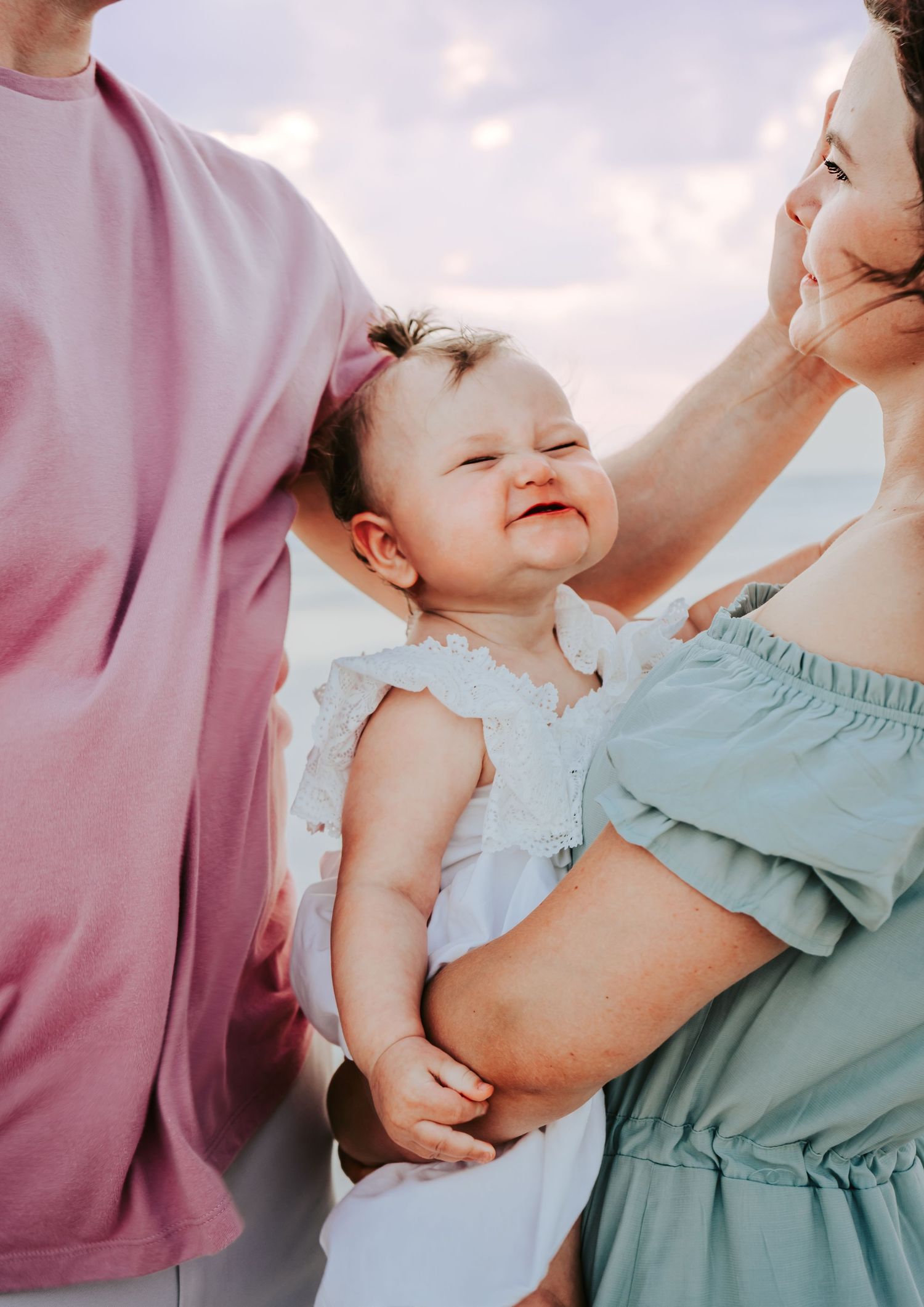 Outdoor Family Session at Indian Rocks Beach in Indian Rocks, FL; baby smiling super big between parents