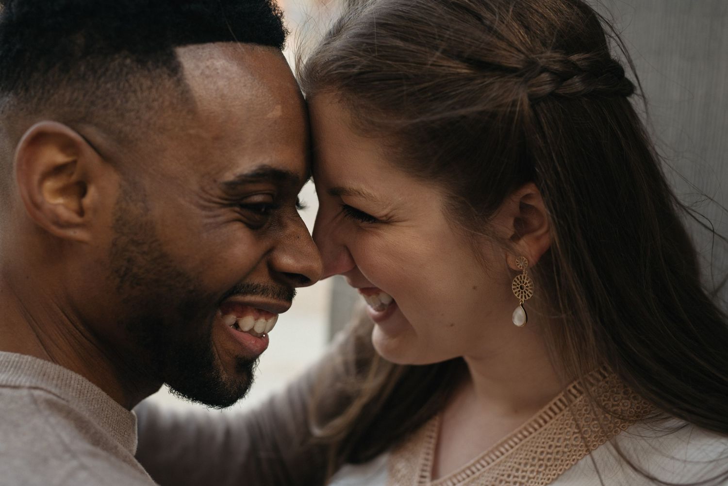 An intimate close-up portrait of a couple sharing a laugh together outdoors.