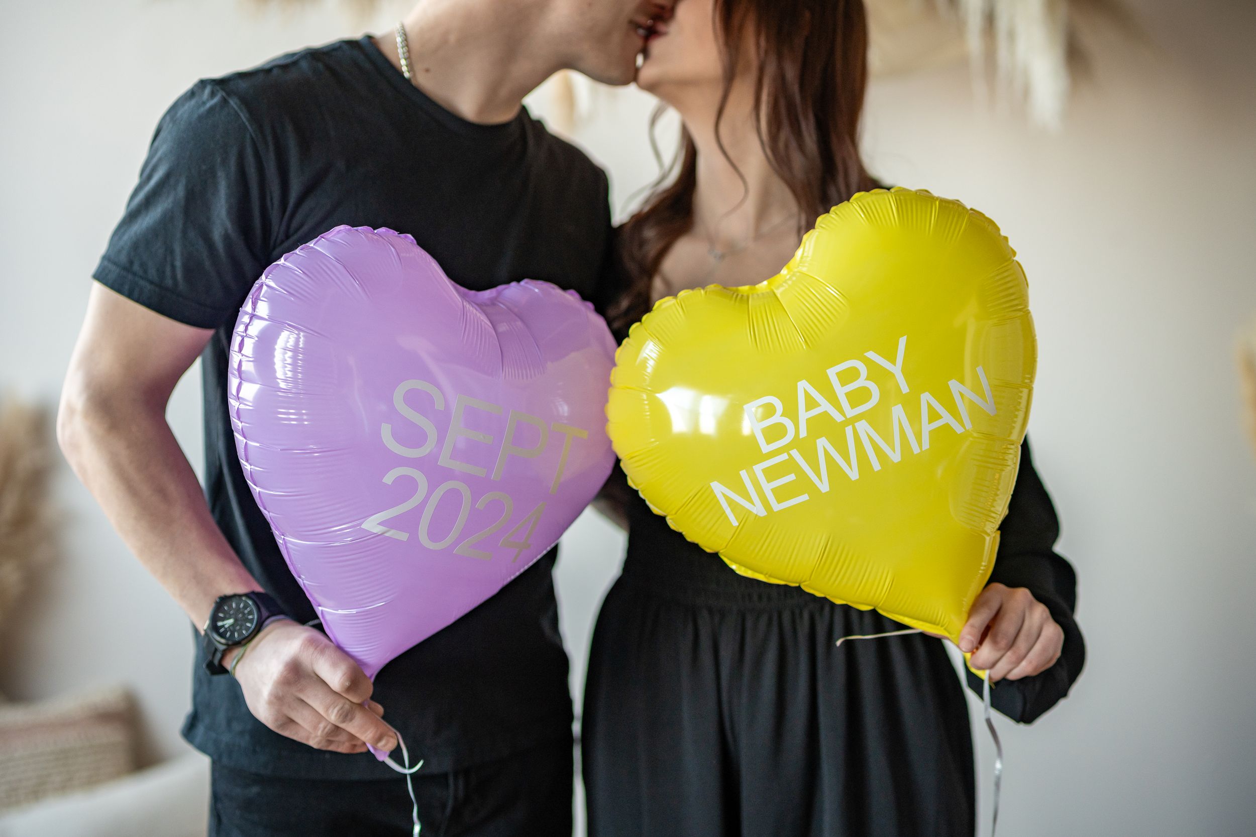 Purple and yellow heart-shaped balloons announce a pregnancy reveal.