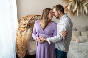 A couple shares an intimate moment in a room decorated with dried pampas grass and wicker furniture.