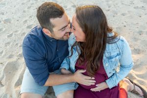 A couple shares an intimate moment while sitting on a sandy beach.