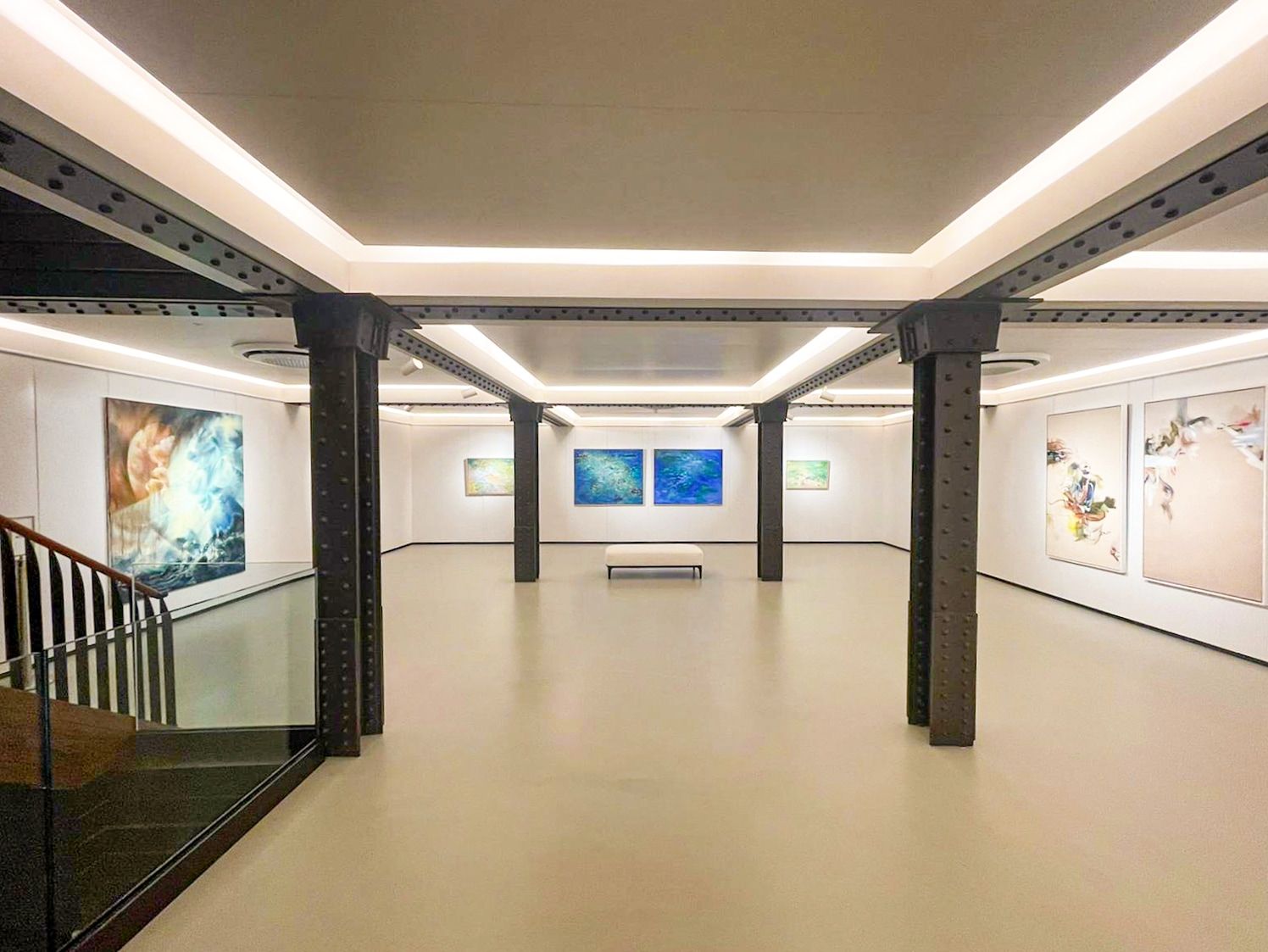 Modern art gallery interior with white walls, black columns and recessed lighting.