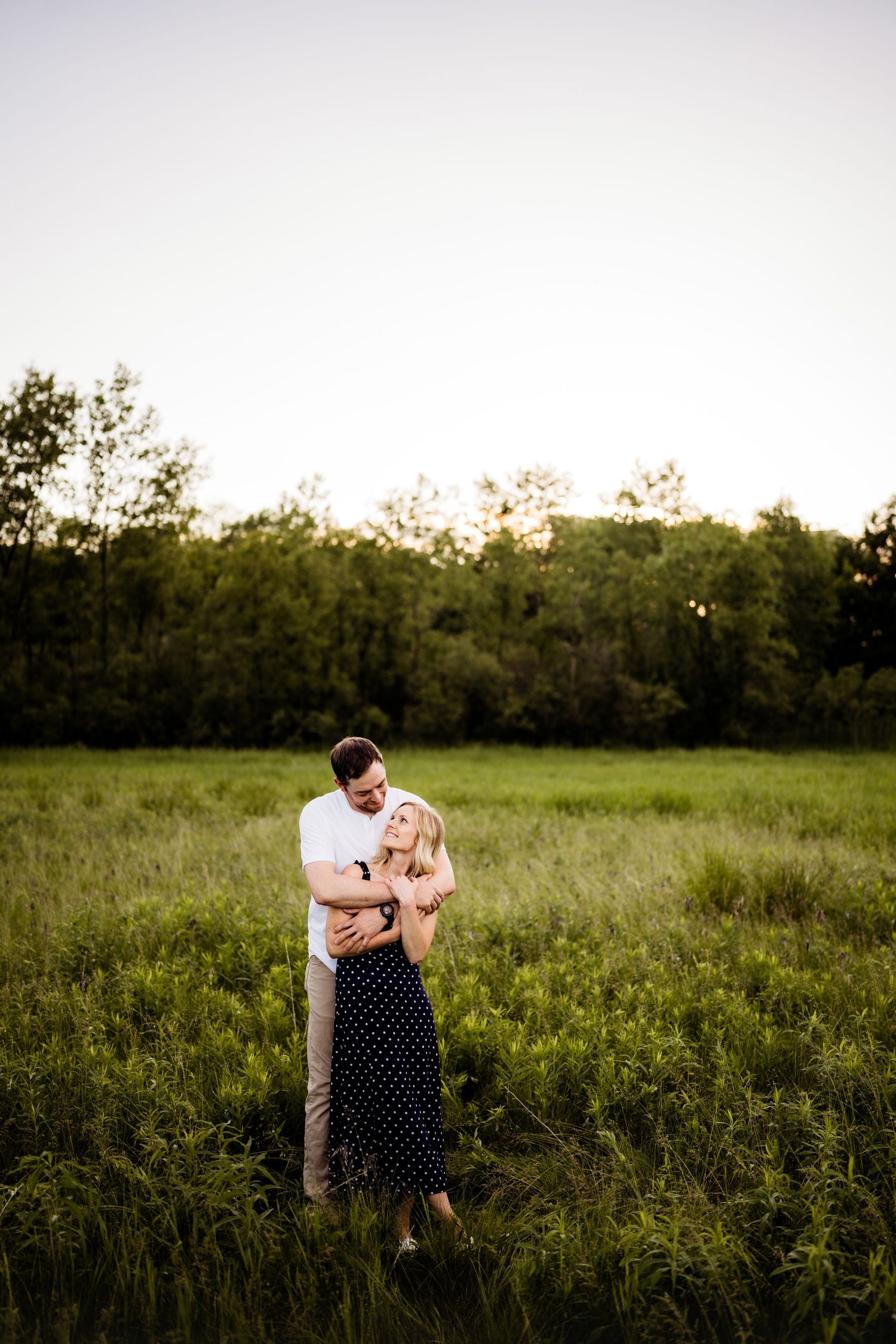 Couple embracing in a peaceful meadow at sunset.