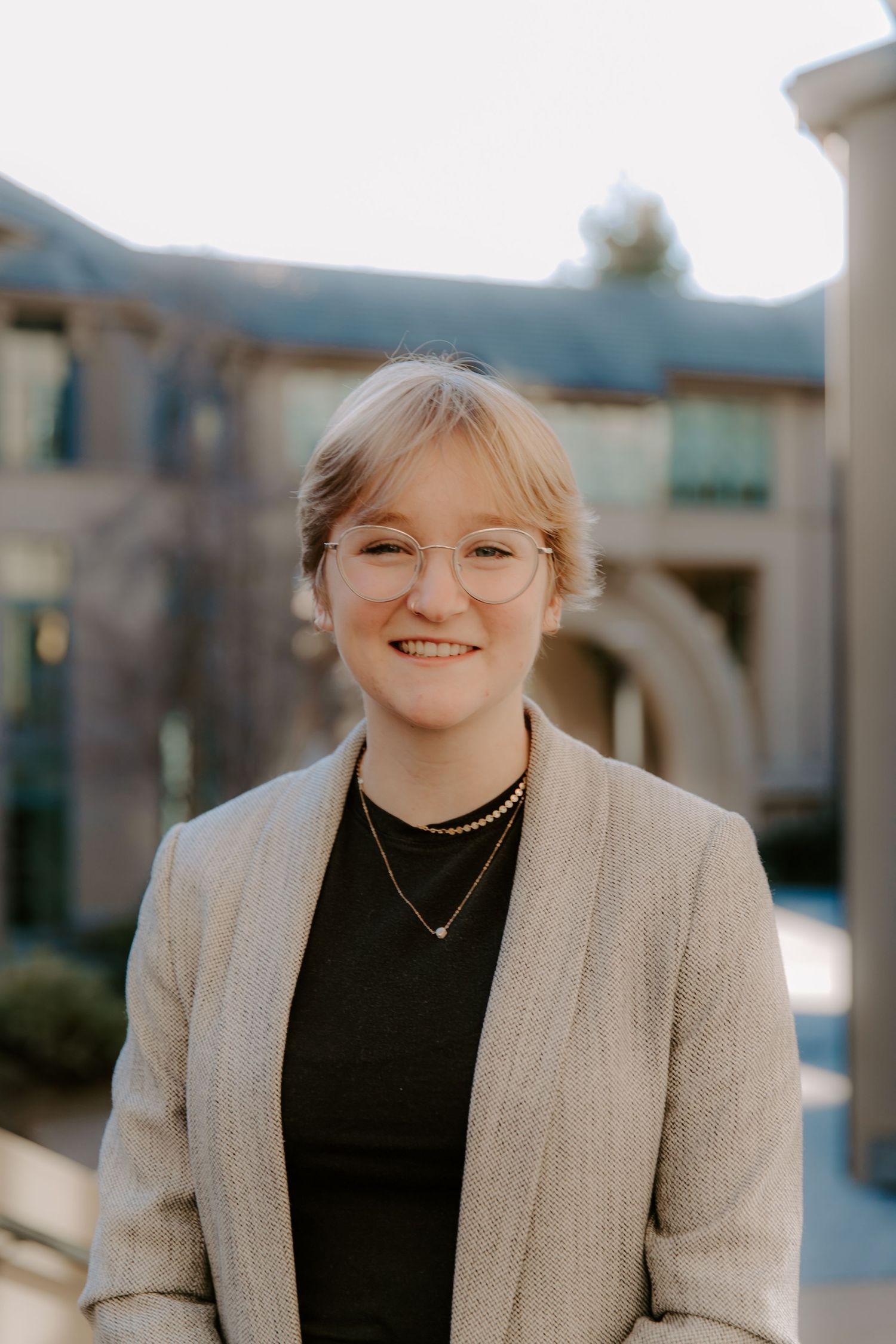 Professional headshots of someone wearing a beige blazer and black top against a blurred outdoor setting.
