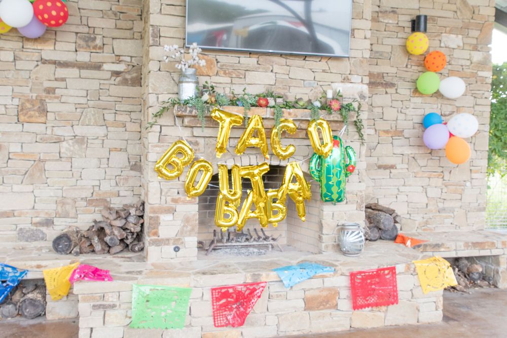 Festive stone fireplace decorated with yellow balloons and colorful banners for a celebration.