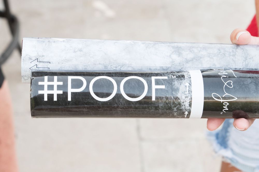 Black and white '#POOF' text decal being held against light background.