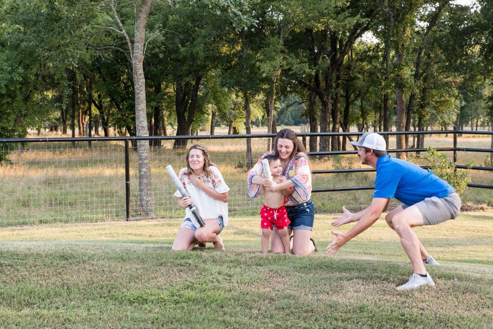 Group celebration in a rural park with pink smoke effects and wooden fencing.