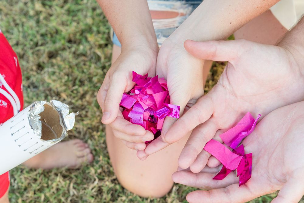 Close-up of hands holding bright pink confetti or powder outdoors.