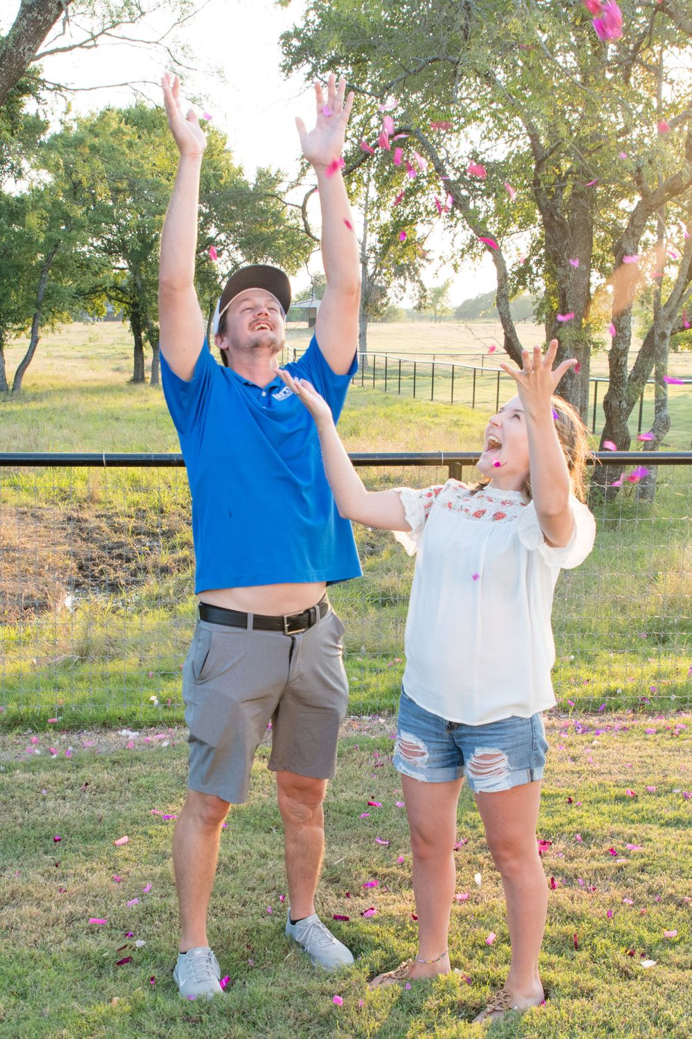 Joyful celebration with arms raised against rustic outdoor backdrop.