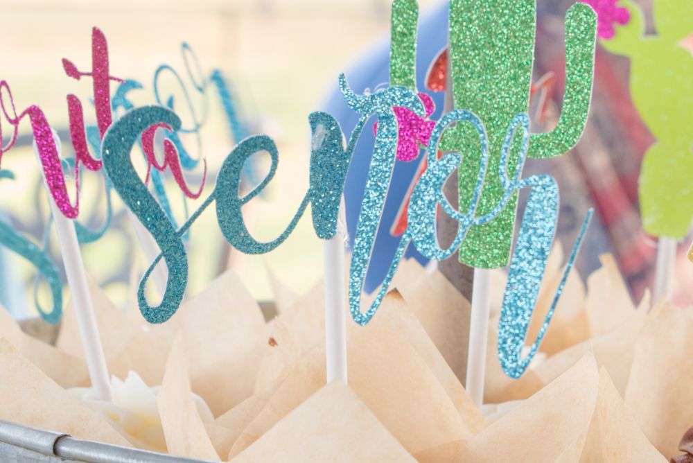 Closeup of sparkly teal and pink party decoration letters against white tissue paper.