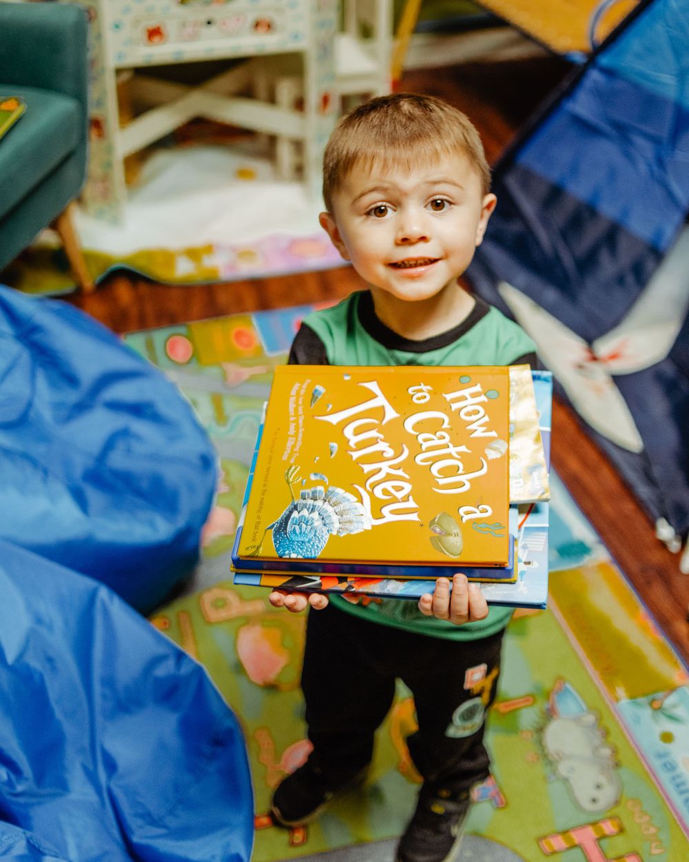 Young child holding a colorful book while standing in a playful bookstore setting.