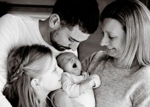 Fun family photo with newborn in the centre yawning in black and white