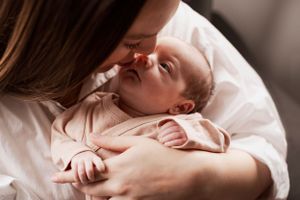 Mother kissing her newborn baby in natural light