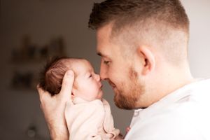 Light airy newborn photo of father and daughter with noses touching