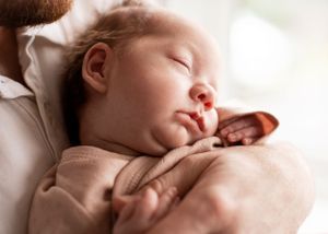 Closeup newborn photography of baby's lips resting on dad's hand
