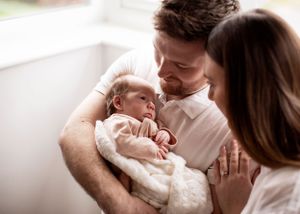 Newborn family photo with dad cradling baby in white studio