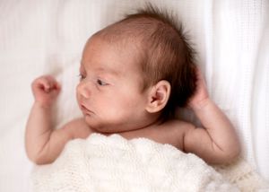 In-home newborn photo of baby covered with a blanket