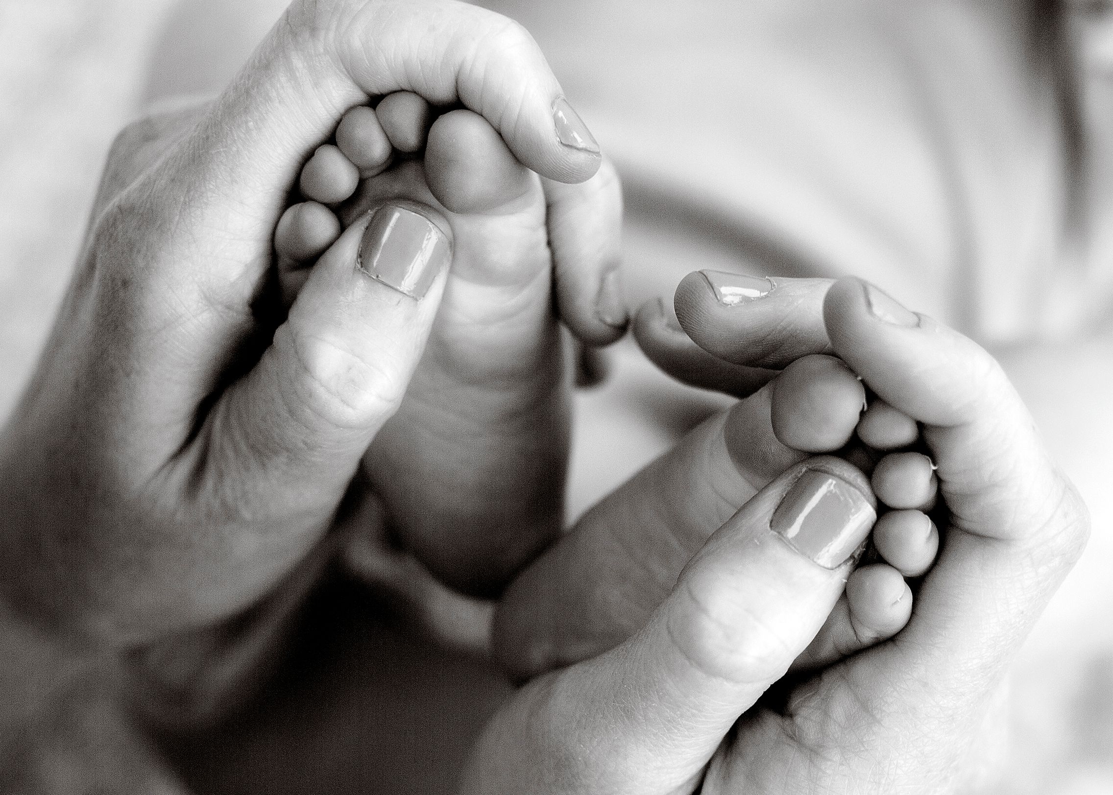 Black and white newborn photography closeup of baby toes in mum's hands
