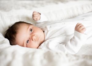 Cute newborn baby photograph lying on white bed